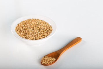 Quinoa grains with spoon and bowl on white background