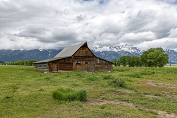 Obraz premium Old mormon barn in Grand Teton Mountains with low clouds. Grand Teton National Park, Wyoming, USA.