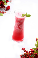 Watermelon juice blended in a clear glass on a white background There is a branch of cherry trees.soft focus.