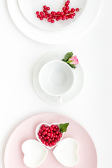set-up table with plates, wineberry and flower on white background top view