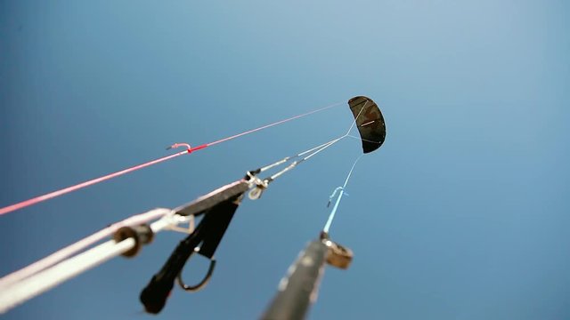 Black half round kite flying freely in sky being kept with three cords in spring