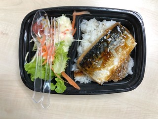 Saba fish grilled with teriyaki sauce on topped rice bowl in the plastic container