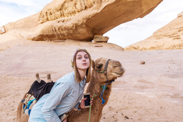 Young woman smiling posing with a camel in the middle of the jordan desert