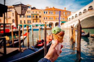 Hand man holds an Italian ice cream on background of Grand Canal and Handol in Venice, Italy....