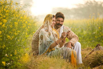 Naklejka na ściany i meble Rural couple holding Indian rupee notes in agriculture field