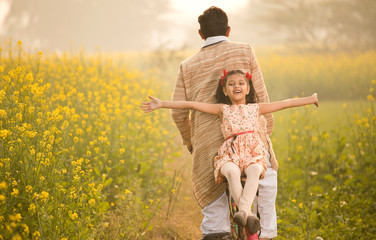 Father with daughter riding bicycle on agriculture field