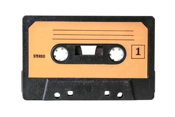 Obraz premium An old vintage cassette tape from the 1980s (obsolete music technology). Black grid plastic body, pale orange label with lines for taking notes and the text Stereo, one.