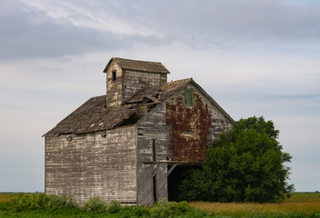 Obraz premium Old wooden barn in rural Central Illinois as the rain clouds start to roll in. LaSalle County, Illinois, USA