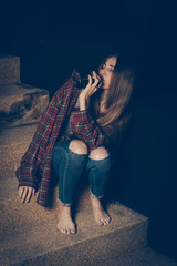 Young drunk woman sitting outside in night. Alcoholism and drug addiction lead to depression.