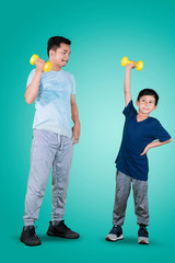 Father and child lifting a dumbbell on studio