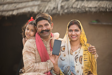 Delighted rural family holding new mobile phone