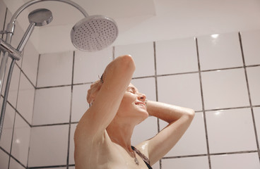 Beautiful young woman taking a shower in the bath with white tiles, cleanliness and hygiene, body...
