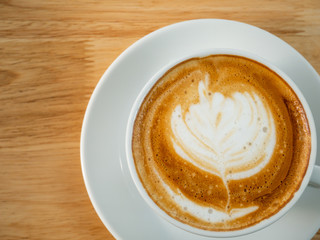 Cup of latte art coffee on wooden table, top view