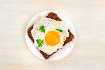 An overhead photo of an egg cooked sunny side up on a toast with a place for text