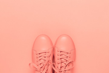 Pair of coral shoes on coral background. Trendy color of 2019. Monochrome image.