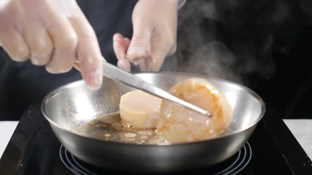 Cooking seafood. healthy food concept. Professional chef in gloves cooking scallops turning them with culnary pliers in slow motion. hd