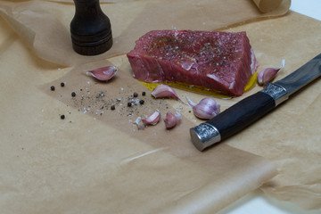 Extreme Close Up view of a Hand Seasoning Cooked piece of Meat in a Bright Light. Chef Accompanying Steak with Garlic, Rosemary, Pepper, Salt. Delicious, Modern Cuisine, Exclusive Recipe. 