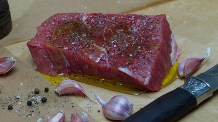 Extreme Close Up view of a Hand Seasoning Cooked piece of Meat in a Bright Light. Chef Accompanying Steak with Garlic, Rosemary, Pepper, Salt. Delicious, Modern Cuisine, Exclusive Recipe. 