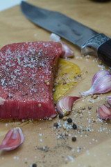 Extreme Close Up view of a Hand Seasoning Cooked piece of Meat in a Bright Light. Chef Accompanying Steak with Garlic, Rosemary, Pepper, Salt. Delicious, Modern Cuisine, Exclusive Recipe. 