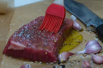 Extreme Close Up view of a Hand Seasoning Cooked piece of Meat in a Bright Light. Chef Accompanying Steak with Garlic, Rosemary, Pepper, Salt. Delicious, Modern Cuisine, Exclusive Recipe. 