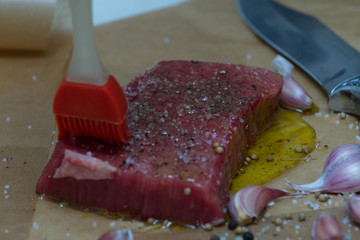 Extreme Close Up view of a Hand Seasoning Cooked piece of Meat in a Bright Light. Chef Accompanying Steak with Garlic, Rosemary, Pepper, Salt. Delicious, Modern Cuisine, Exclusive Recipe. 
