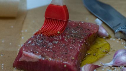 Extreme Close Up view of a Hand Seasoning Cooked piece of Meat in a Bright Light. Chef Accompanying Steak with Garlic, Rosemary, Pepper, Salt. Delicious, Modern Cuisine, Exclusive Recipe. 