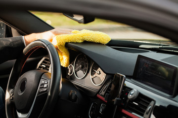 Clining car. Wiping panel of a luxury car with yellow microfiber, close-up view
