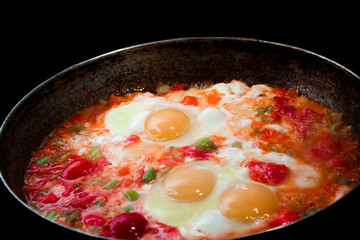 morning omelet on big cast iron pan on black background