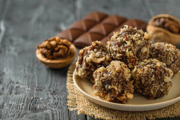 Hand-made balls of dried fruits, nuts and chocolate on a wooden table.