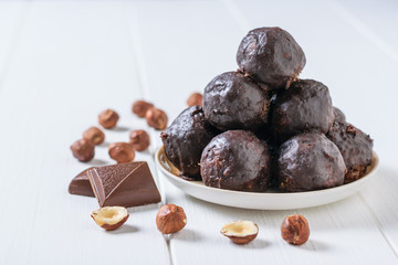 Hand-made balls of dried fruits, nuts and chocolate on a white wooden table.