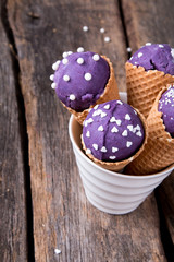 Ice cream scoops in sweet cone on wooden table. 