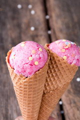 Ice cream scoops in sweet cone on wooden table. 