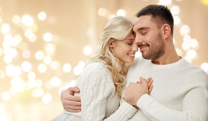 love, valentines day and people concept - happy couple hugging over festive lights on beige background