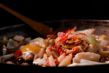 morning omelet with wooden spatula on big cast iron pan on black background
