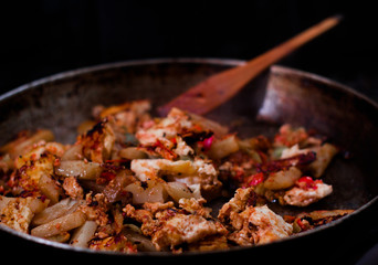 morning omelet with wooden spatula on big cast iron pan on black background