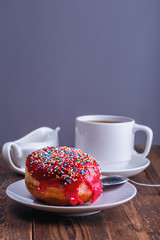 fresh tasty chocolate donut and a cup of black tea with milk jug for breakfast