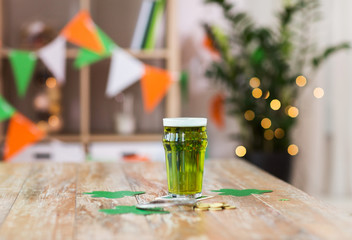 st patricks day, holidays and celebration concept - glass of green beer with horseshoe, shamrock and gold coins on wooden table