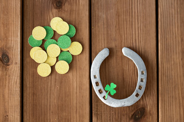 fortune, luck and st patricks day concept - horseshoe with shamrock on wooden background