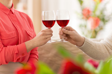 valentines day, romantic date and holidays concept - hands of couple drinking red wine and clinking glasses at home