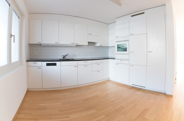 modern bright kitchen in an empty refurbished apartment with black granite work surface and wooden parquet floor