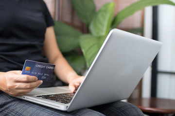 Young woman holding credit card and using laptop computer. Online shopping concept. Copy space.