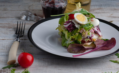 fresh salad fitness. with arugula leaves of beet quail eggs and tomatoes cherry.It is put on a white plate and a cake table