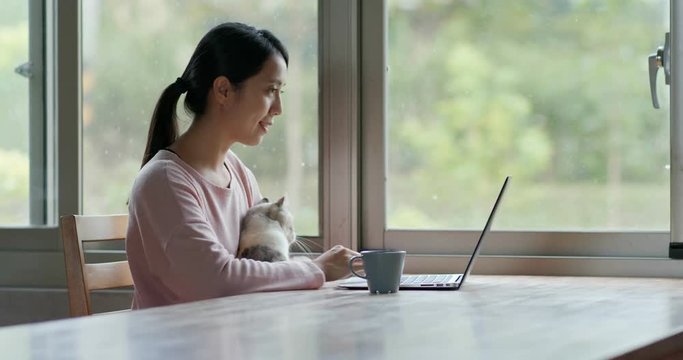 Woman work on laptop computer with her cat at home