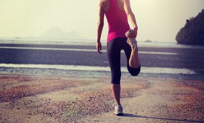 Healthy lifestyle woman stretching legs on beach
