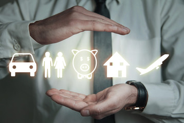 Businessman protecting car, family, piggy bank, house and airplane icons. Insurance