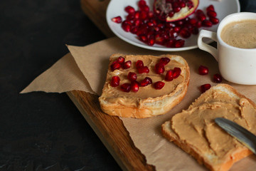 Sandwich with peanut paste and pomegranate grain red - breakfast or sweet snack (dessert). Top view. copy space