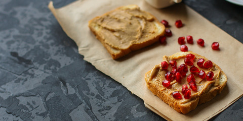 Sandwich with peanut paste and pomegranate grain red - breakfast or sweet snack (dessert). Top view. copy space