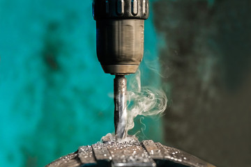Drilling the metal with spiral drill with smoke