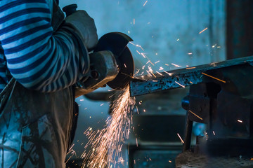 Working man with angle grinder, process of cutting carbonated steel metal with quantity of sparks...