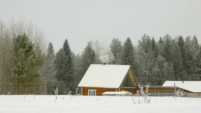 Human simple homes. Mastering the wild lands. Human vital activity. Smoke comes from the chimney. Winter period.